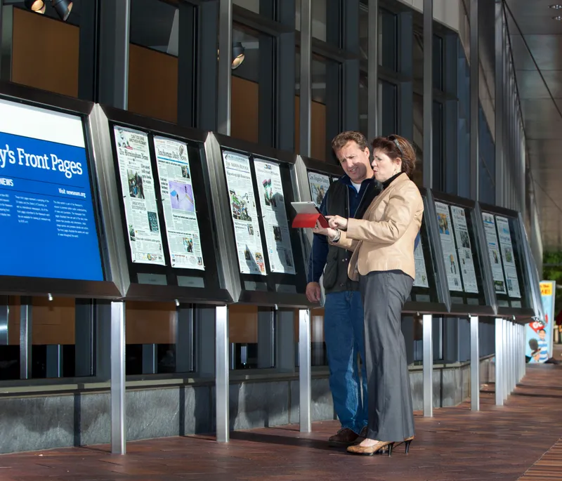 Heidi Berenson with a client beside newspaper front-page displays